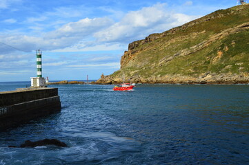 Fototapeta na wymiar Un bateau rouge entre dans le port de Pasaia, au Pays Basque