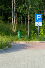 Pojemnik na śmieci na parkingu przy lesie z miejscem wyznaczonym dla niepełnosprawnych. - obrazy, fototapety, plakaty