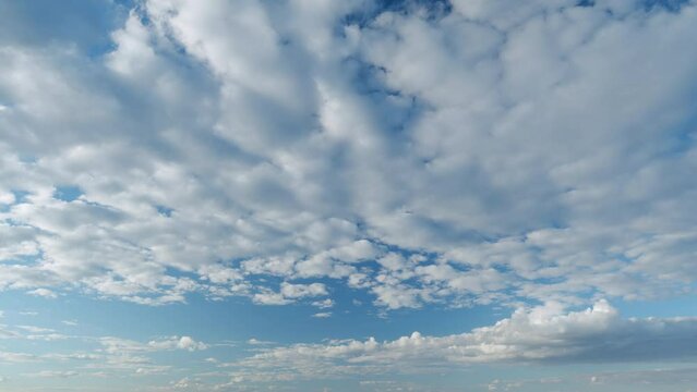 Sky with bautiful silky clouds. Puffy fluffy cumulus and cirrocumulus on different layers clouds. Timelapse.