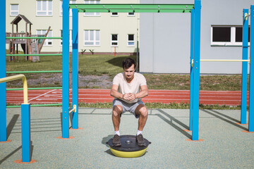 Professional athlete performs a squat with his own weight on a balance apparatus for a more intense...