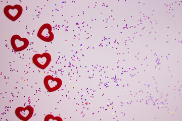 Red hearts with purple glitter over the pink background with copy space
