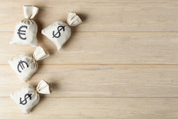 Money bags with Euro and USD symbols on wooden background with copy space
