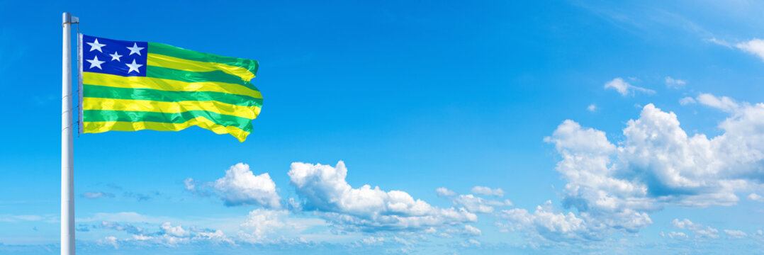 Goi&aacute;s - state of Brazil, flag waving on a blue sky in beautiful clouds - Horizontal banner
