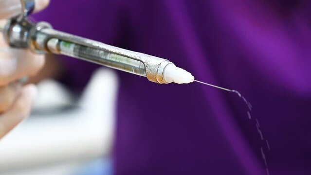 Dentist assistant hand in white glove holding syringe with anesthesia Releasing Drug. Usage of Sterile Equipment. Close-up shot of dentist holding syringe with anesthetic