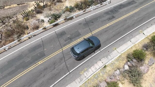 Aerial drone shot of a moving car along a highway with rocks and plants on the hills in colca canyon chivay peru south america 