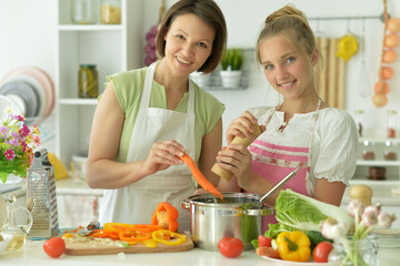 Beautiful girl with her mother preparing a salad in the kitchen