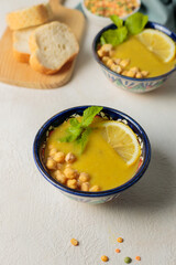 Vegetarian soup of lentils and chickpeas with mint and lemon. Close-up on a light background