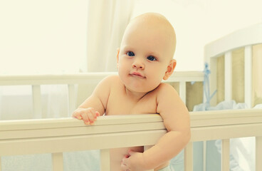 Portrait of cute baby sitting in the bed at home