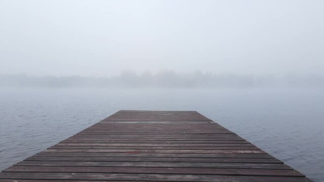 wooden pier pier in the fog on the lake in autumn . moving the camera forward