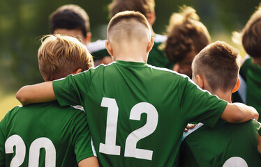 Teenage boys freindship in a sports team. Group of sports players huddling in a circle and motivating each other. Boys in green jersey shirts with numbers