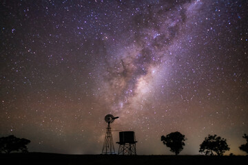 Milky Way rising over a windmill silhouette in a rural setting