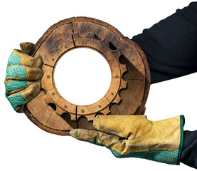 Hands with protective work gloves holding a cross section of a tree trunk with a wooden gear...