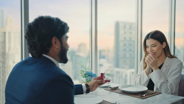 Happy couple marriage proposal young businessman propose to girlfriend with wedding ring enjoy surprise engagement at restaurant city view