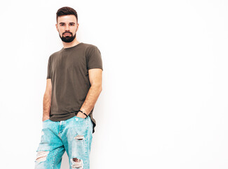 Portrait of handsome confident stylish hipster lambersexual model.Man dressed in T-shirt and jeans. Fashion male isolated on white wall in studio