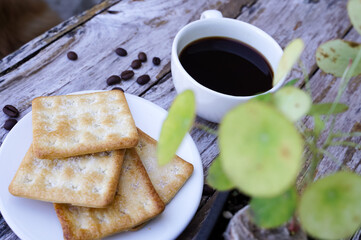 The hot black coffee in a white cup and the crackers are intense and go well together.