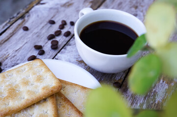 The hot black coffee in a white cup and the crackers are intense and go well together.
