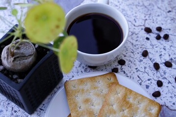 The hot black coffee in a white cup and the crackers are intense and go well together.