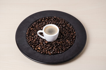 Roasted coffee espresso beans on dark plate background and cup with crema, close-up still life hot beverage, I love coffee concept