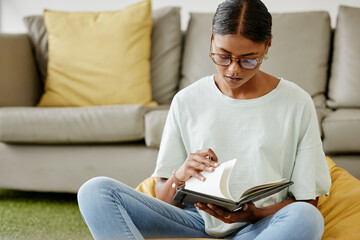 College student woman writing notebook, reading research and learning for education, knowledge or project on campus floor in Brazil. University youth, focus studying and journal notes in school books