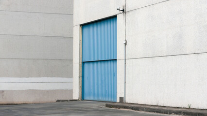 Obraz na płótnie Canvas Puerta metálica azul en nave industrial de hormigón 