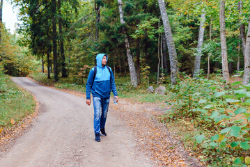 Obraz premium A middle age male hiking with a backpack.Man walks along the autumn forest path way.A healthy lifestyle in nature.