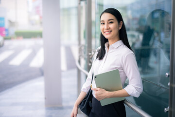 Asian businesswoman holding a tablet looking away smart business concept, smart woman .