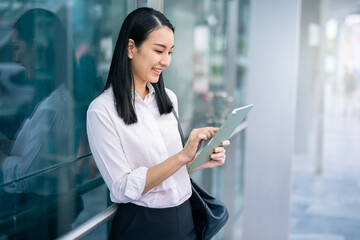 Obraz premium Asian businesswoman holding a tablet looking away smart business concept, smart woman .