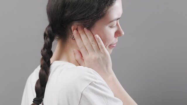Portrait of young Caucasian woman holds her ear with her palm. Close up. Back view. The concept of hearing loss, otitis media and tinnitus.