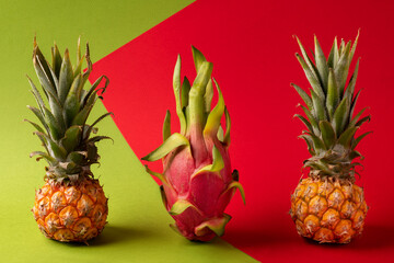 Baby pineapple, pitaya, pitahaya, dragon fruit on tomato and green abstract background.