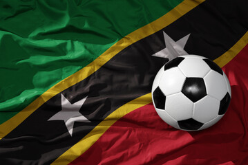Fototapeta premium vintage football ball on the waveing national flag of saint kitts and nevis background. 3D illustration
