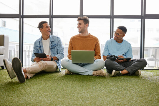 Laptop, tablet and businessmen in creative office working online for startup career. Work, business and digital technology in ecofriendly workplace. Team of men talking on floor in workspace