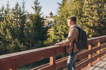 Fototapeta premium Tourist with backpack enjoying beautiful landscape view. Portrait of teenage boy hiker resting in nature. Active lifestyle. Concept of local travel