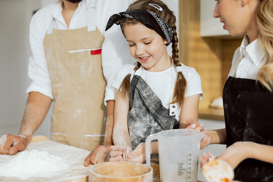 Pretty girl holding flour in hands helping father sieving kneading dogh for homemade pizza.