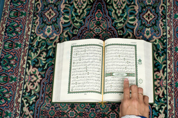 Obraz premium A woman's finger points to a verse in Al-Qur'an