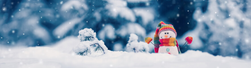 Little knitted snowman on the white snow on blue background.