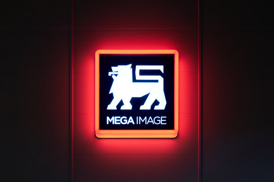 Illuminated Mega Image logo sign at night. Mega Image is a supermarket chain, established in Romania in 1995, owned by Koninklijke Ahold Delhaize N.V. Bucharest, Romania - October 2, 2022.