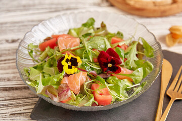 Healthy pescetarian salad with smoked salmon, vegetables, greens and edible flowers.