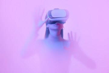 Virtual reality. Young girl in VR eyewear, immersed in clouds of smoke, fog on a pink neon background with a backlight diffuser.