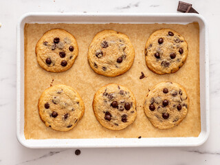 Homemade fresh from the oven on a white metal baking tray American chocolate chip cookies, top view horizontal 