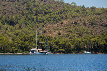 Yachts in the sea in the sunlight over beautiful big mountains background, luxury summer adventure, active vacation in Mediterranean sea, Turkey