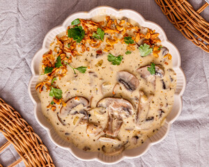 vegan creamy Mushroom soup with crispy fried onions and fresh parsley in a plate closeup top view on a grey linen table horizontal image