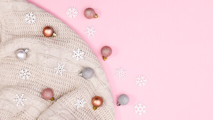 Winter background with Chrismtnas ornaments on sweater on pastel pink background. Flat lay