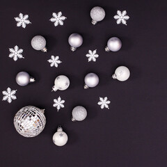 Black background with silver Christmas ornaments and copy space. Flat lay
