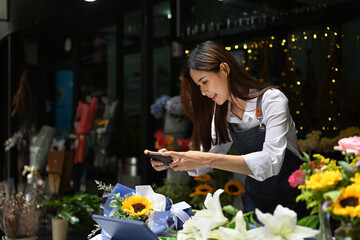 Pretty woman florist taking photo of finished flowers bouquet for social media. Floristry, business and technology concept