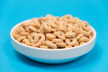 Quick cereal breakfast in the form of rings on a plate on a blue background