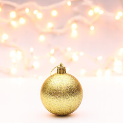 Glitter golden ornament Christmas ball on white background with decorativelights