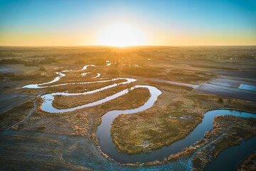 Sunrise over the meandering river. The meandering river over frozen plains.  - obrazy, fototapety, plakaty
