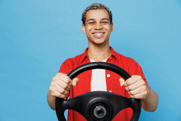 Young cheerful happy fun man of African American ethnicity 20s he wearing red shirt hold steering...