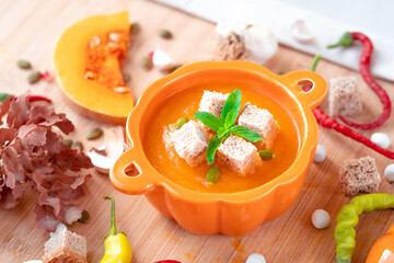 Warm and healthy pumpkin soup with croutons and mint in pumpkin shaped bowl