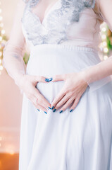 Young pregnant woman with dark hair in airy dress in a room decorated with pine needles and sparkling garlands for Christmas. Christmas mood . Pregnancy